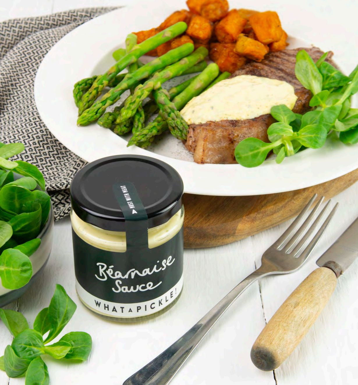 A jar for Béarnaise Sauce next to a plate of pork and veg